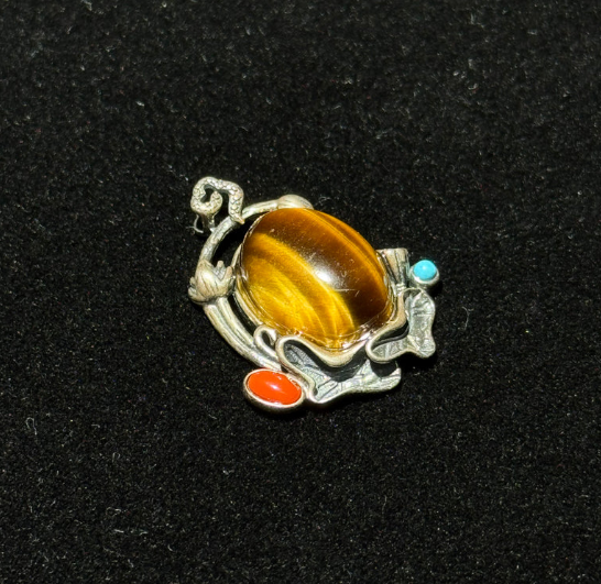 Natural tiger's eye cabochon pendant with vintage-style ethnic metal setting.